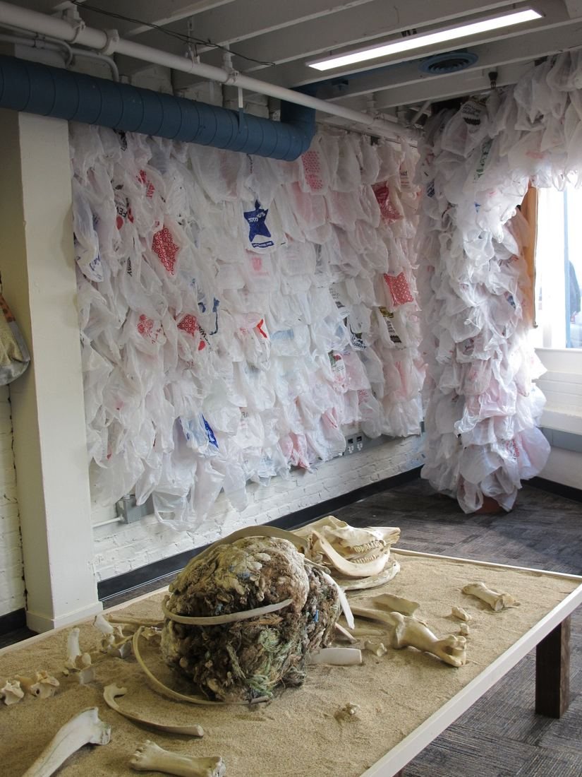 A towering curtain of white and printed plastic bags filling a gallery corner