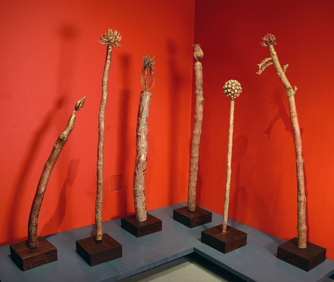 Insect Totems, six bark beetle totems standing on plinths against a bright red wall