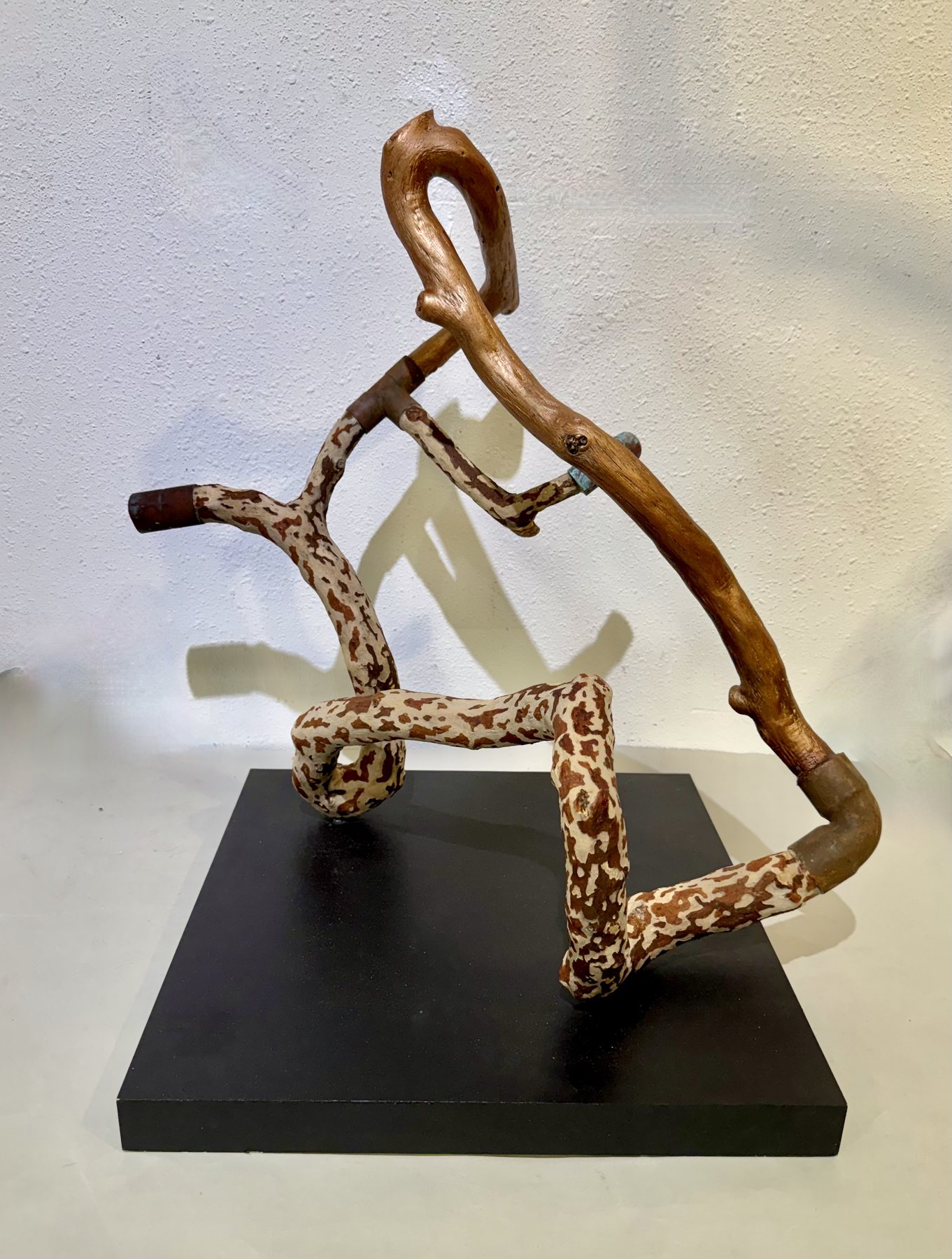 Giraffe, a tall branching wood form, pale with dark speckling, standing on a black plinth