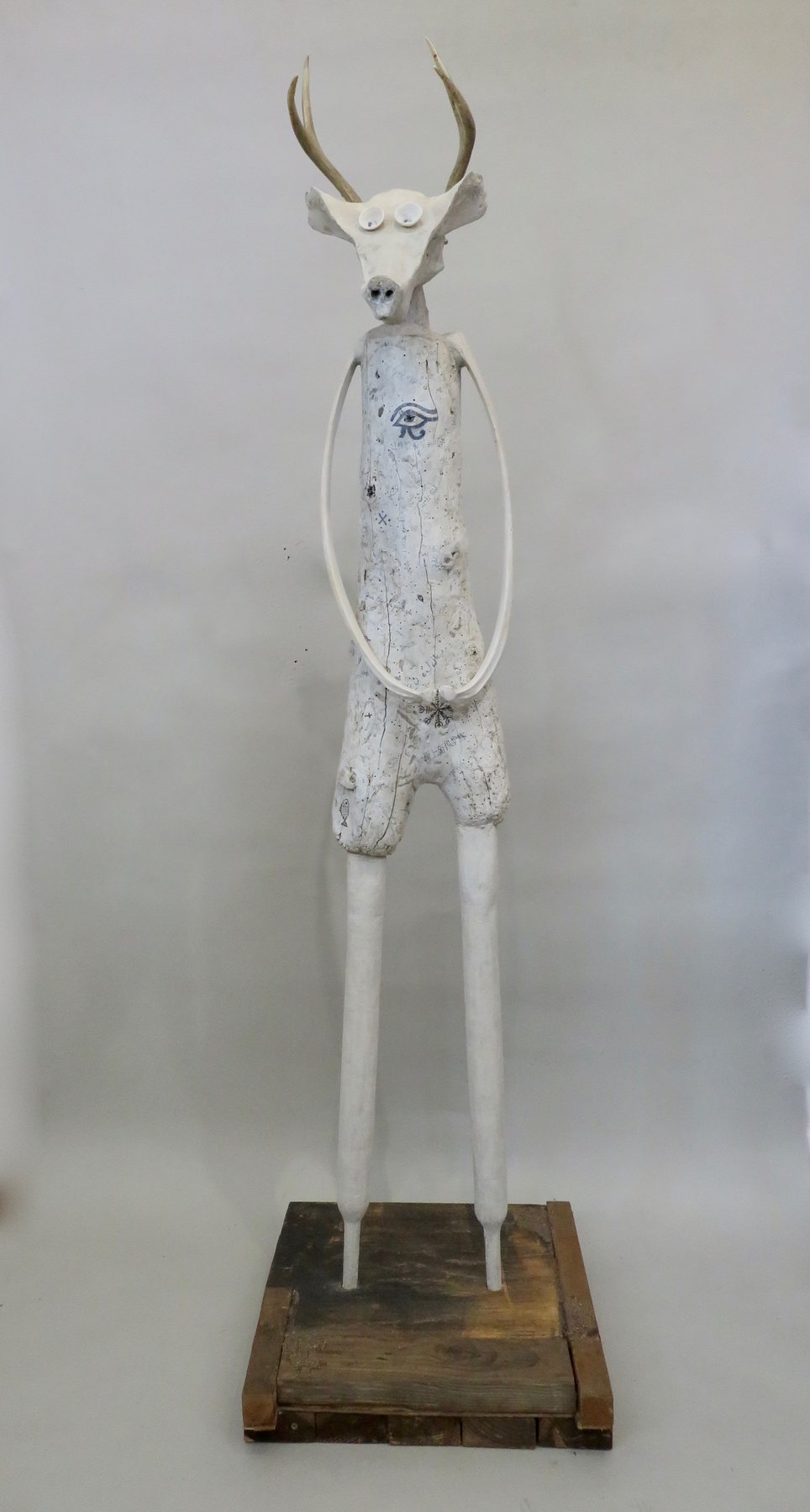 A guardian figure with a horned head on a wooden base