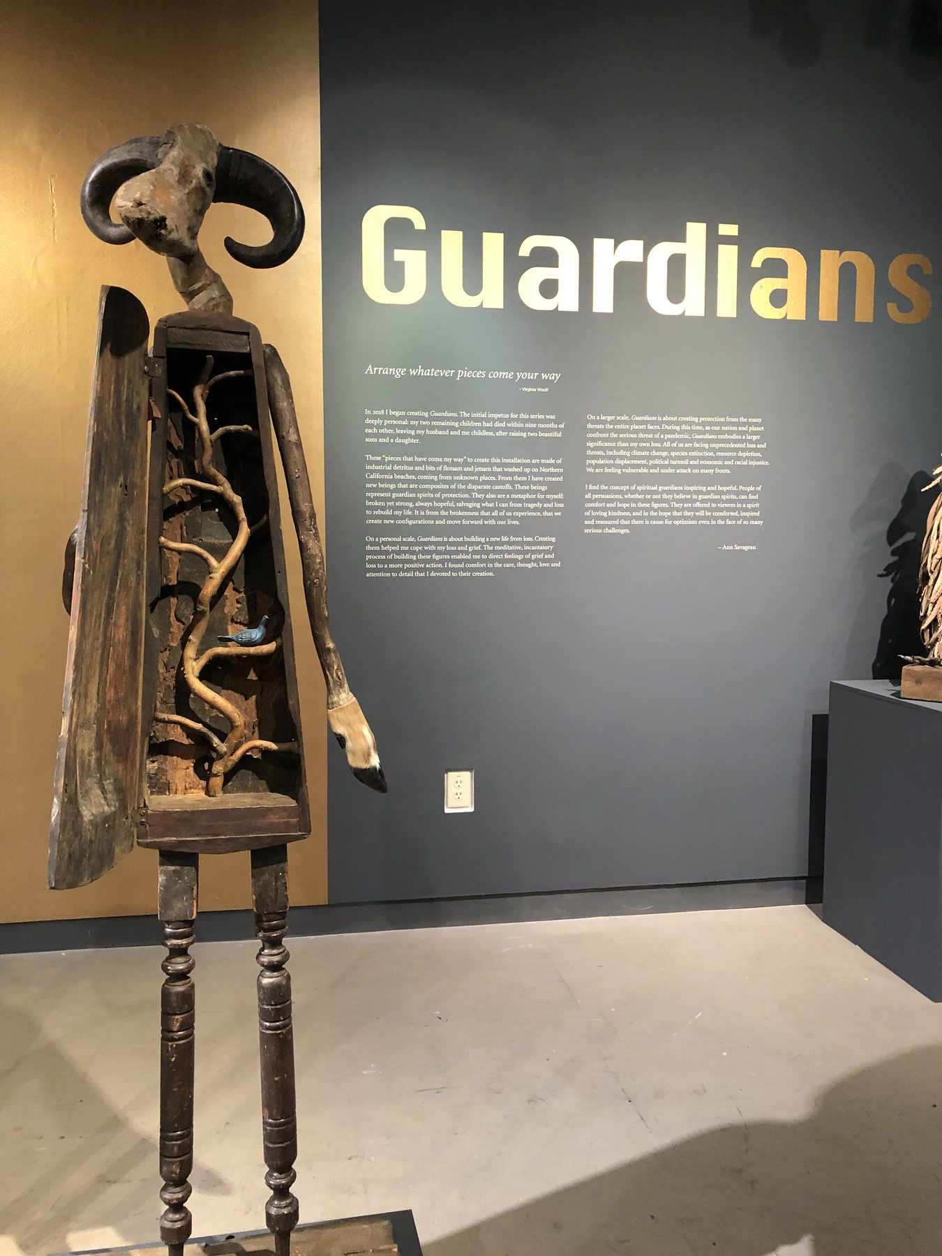 A guardian with a feathered skirt beside the title wall