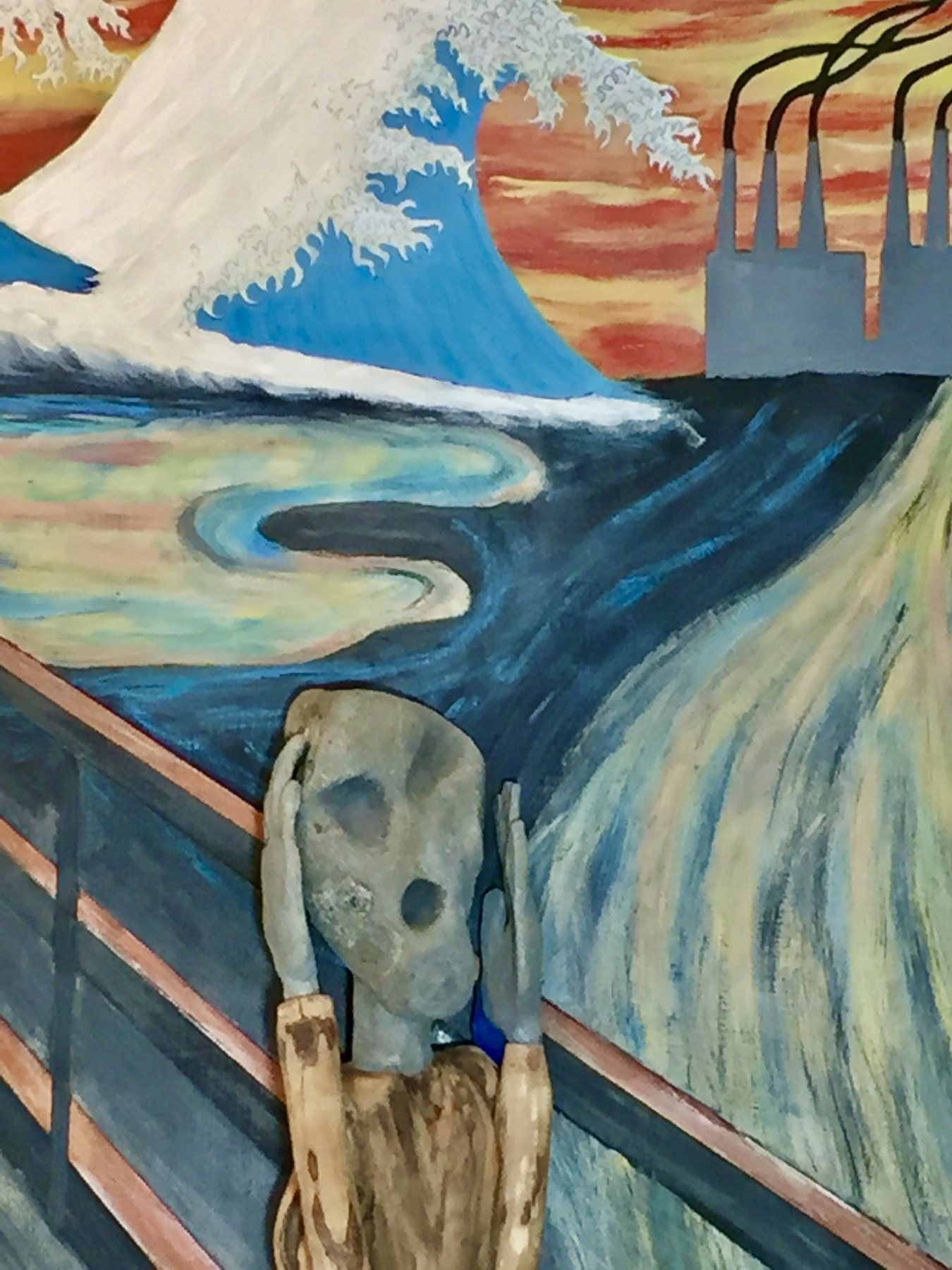 Scream, a beach rock head on a driftwood body against a painted wave