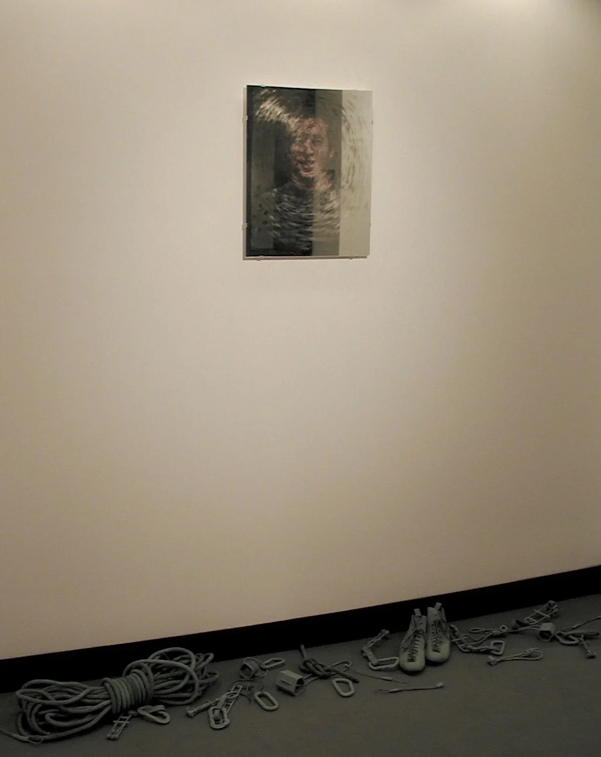 A photograph behind a partially silvered mirror above bronzed climbing gear