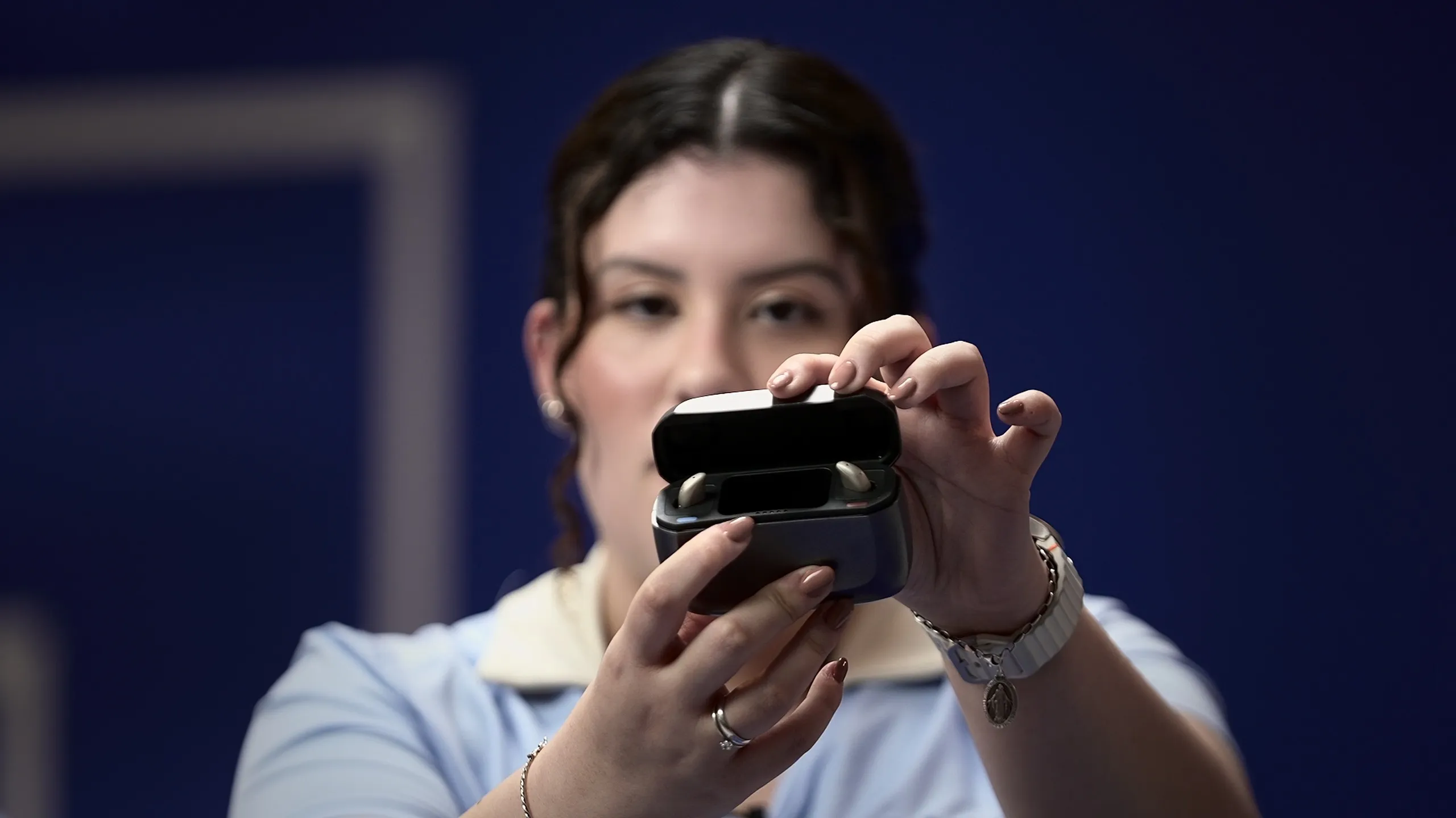 Apresentadora abre o estojo e mostra os aparelhos auditivos