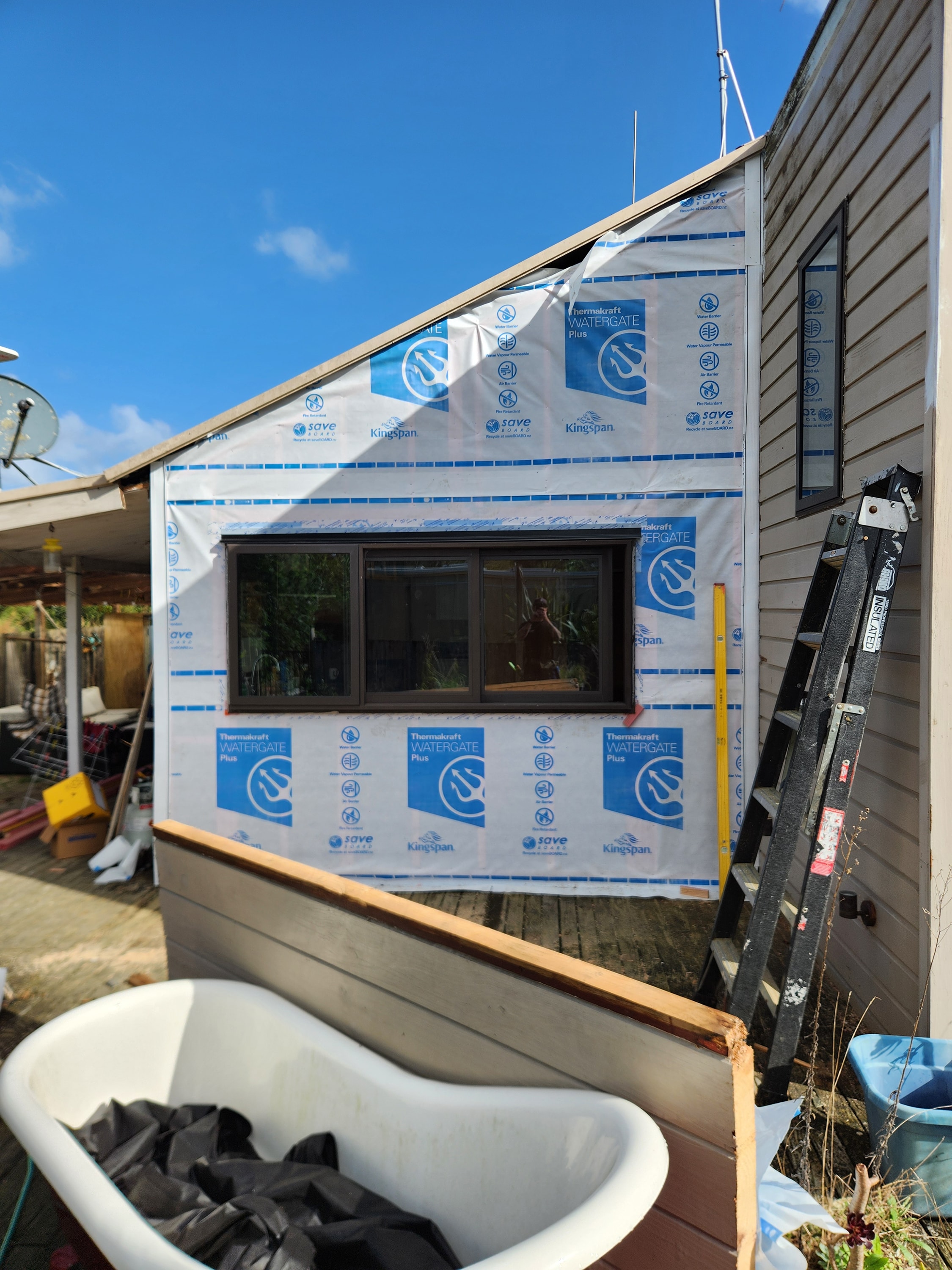 Weatherboard re-cladding in progress with new building wrap and window
