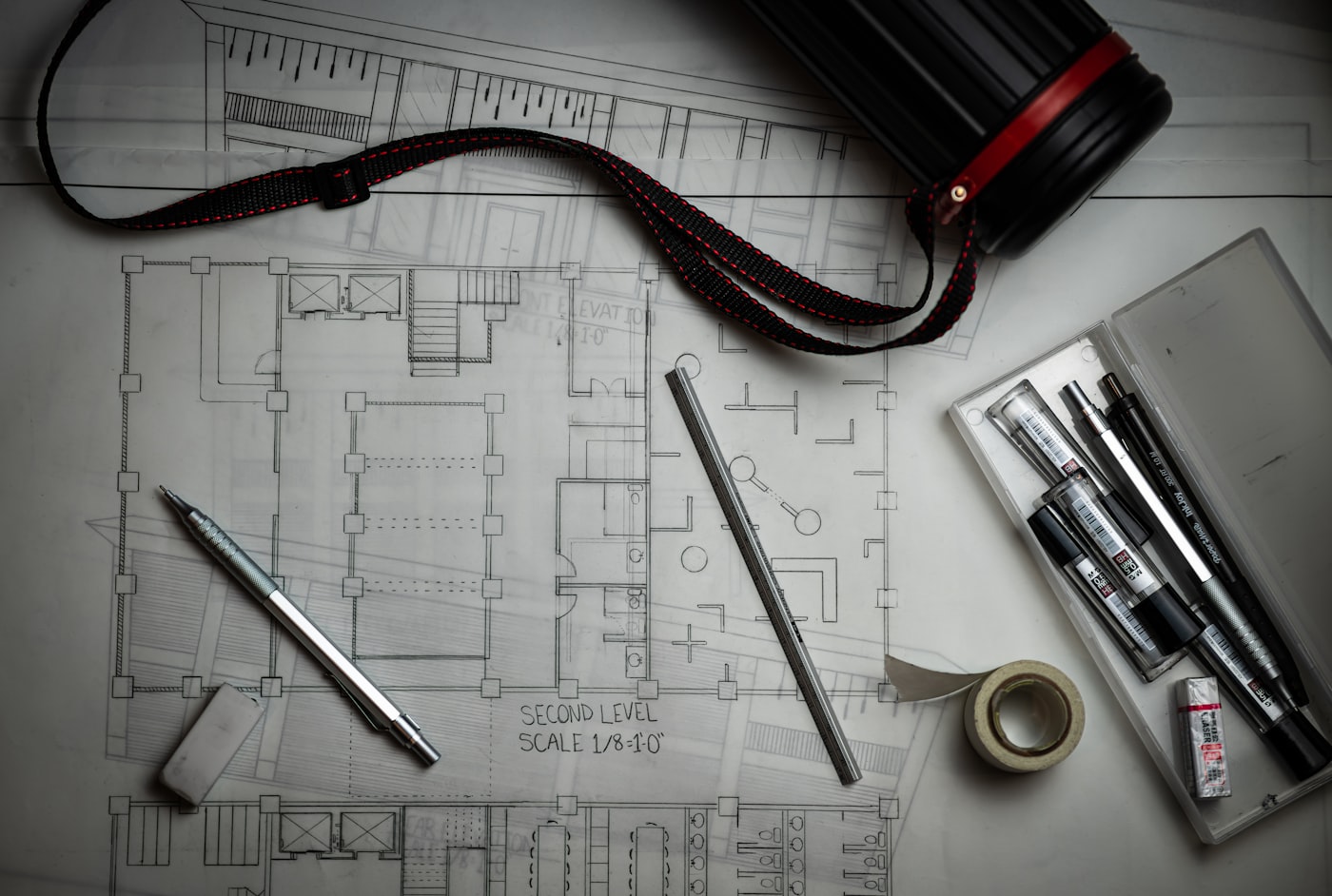 Architectural drawings with drafting pencils, a metal ruler and a storage tube