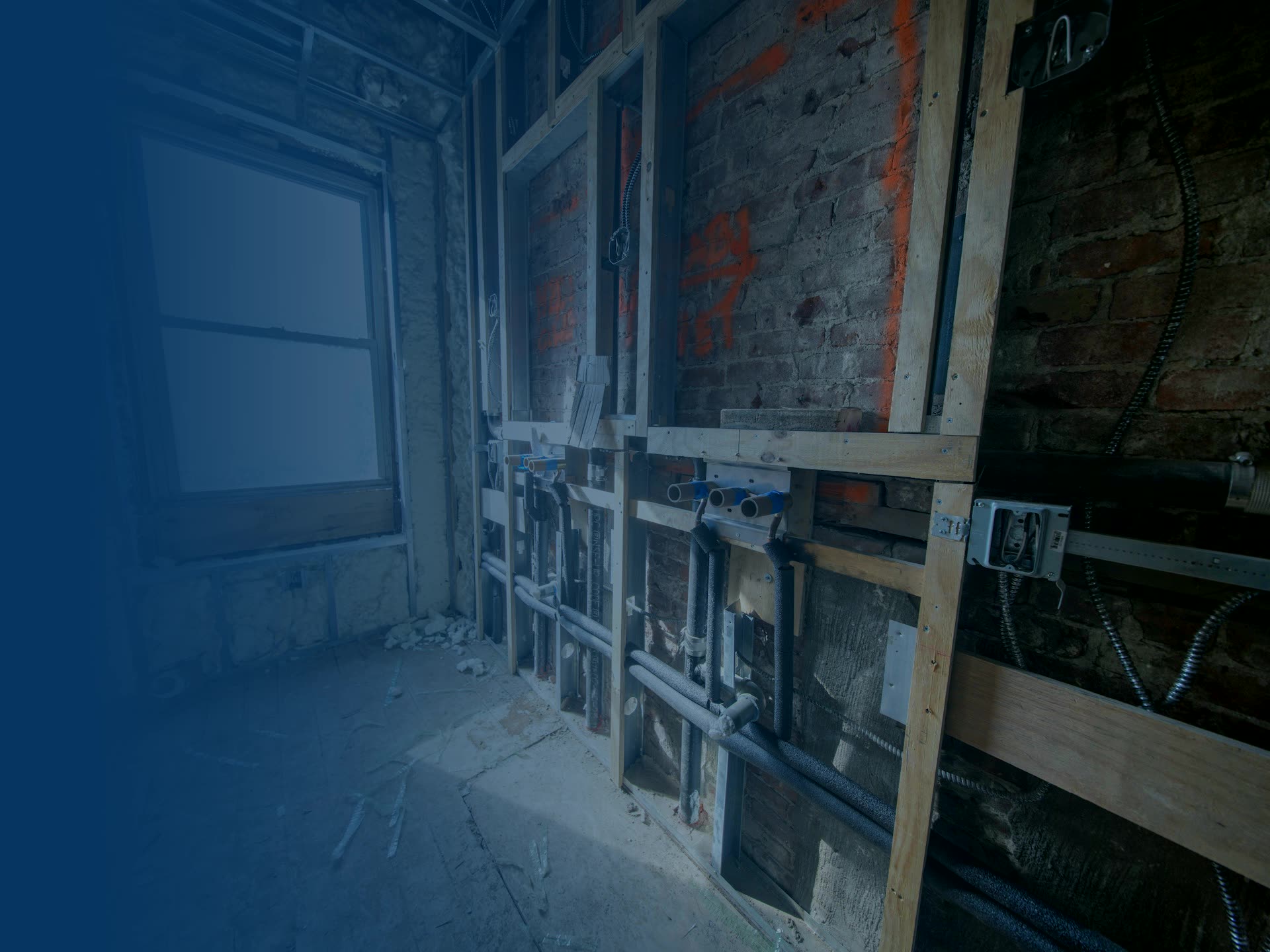 Room under construction with electrical back-boxes and conduit on an exposed stud wall