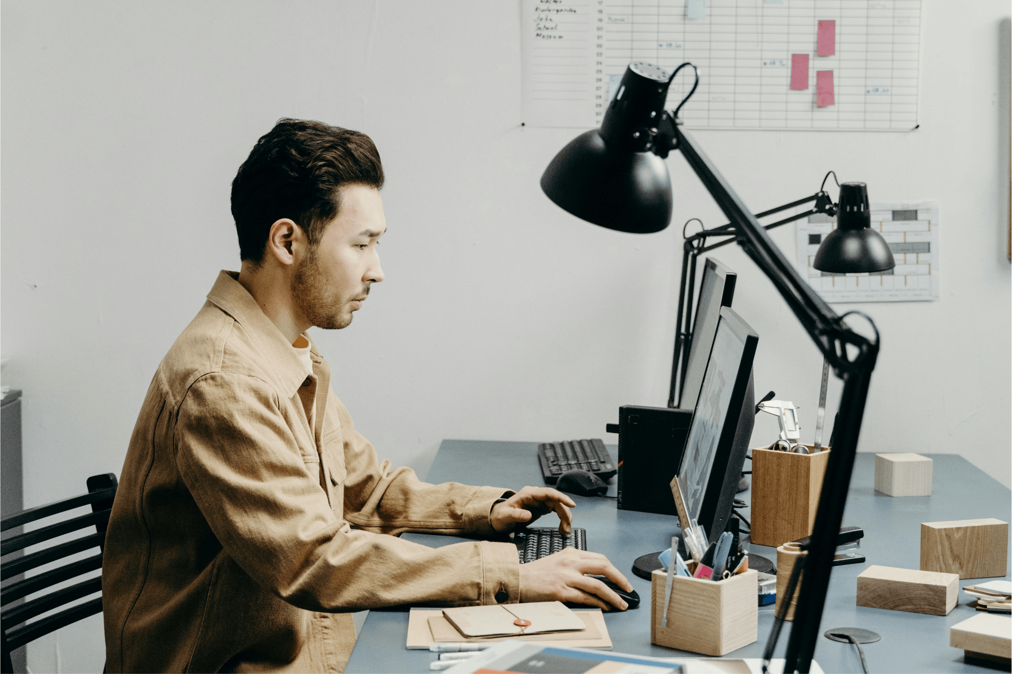 A man typing on a laptop at a well-lit desk, illustrating how proper task lighting supports everyday work, reading, and independence at home