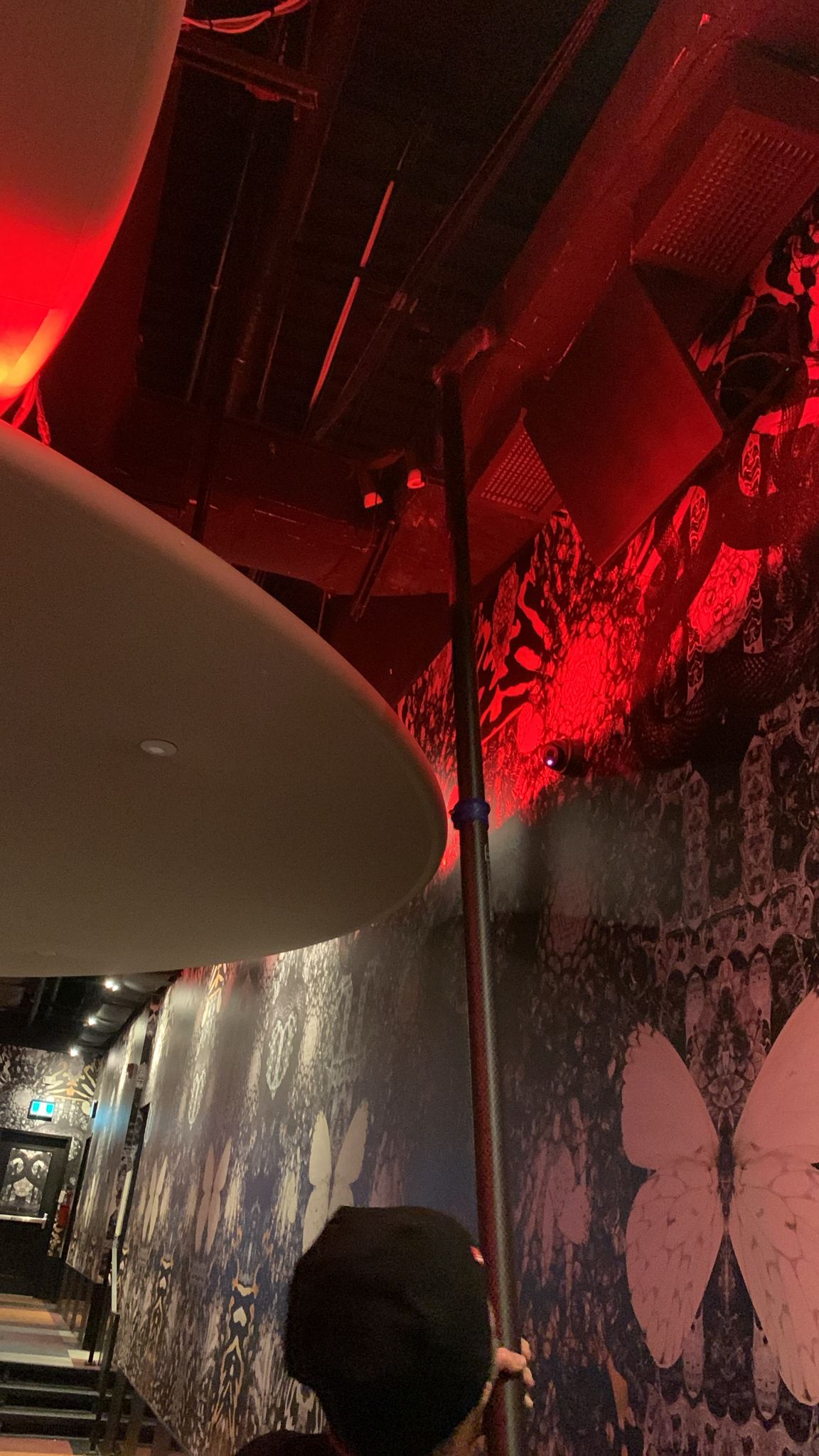 Extension pole cleaning overhead ductwork under red stage lighting at Rebel nightclub in Toronto