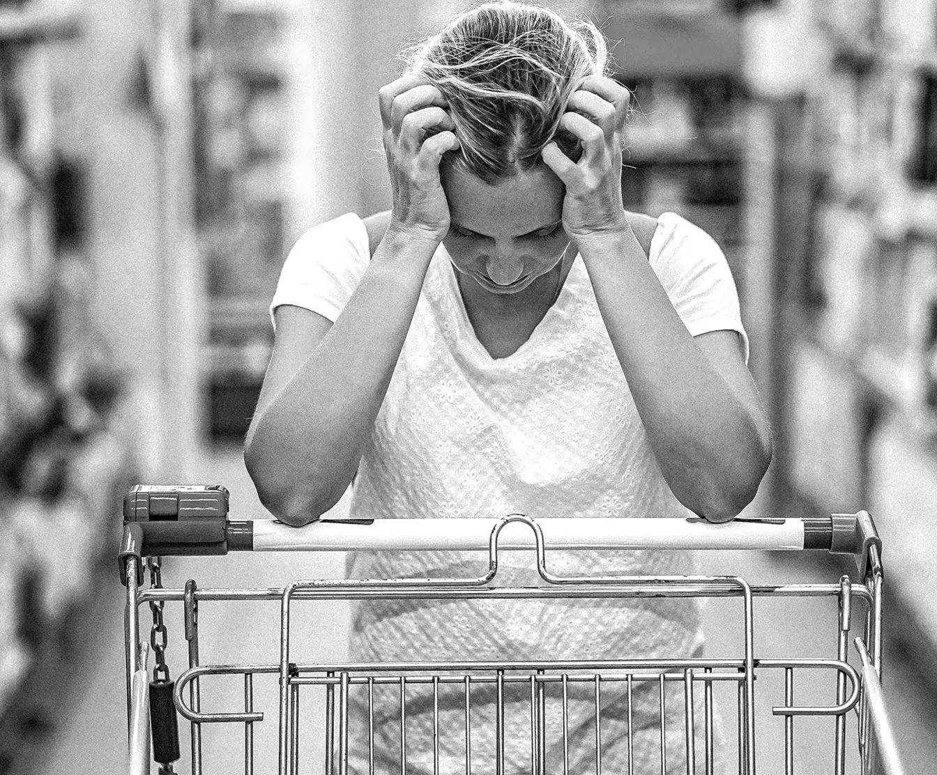 A stressed shopper leaning on a supermarket trolley