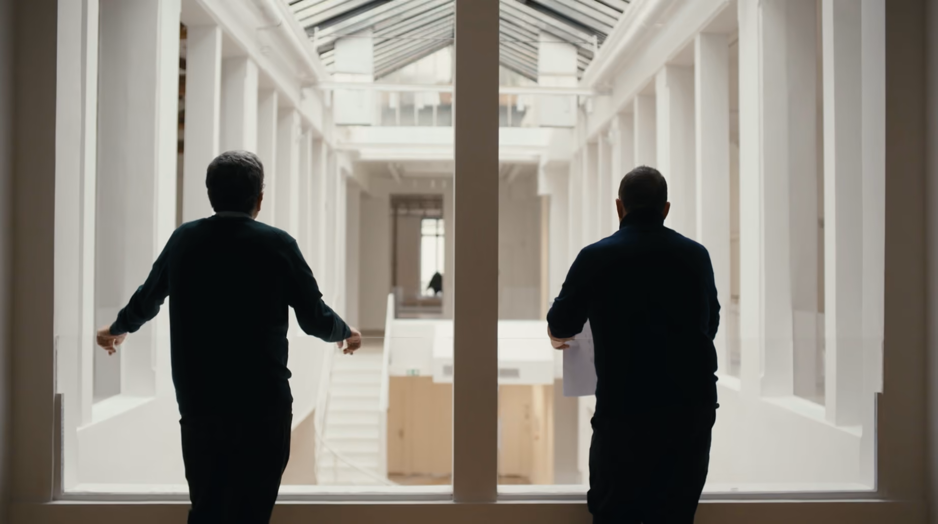 Two men walking through the white exhibition hall of Galerie Joseph in Paris