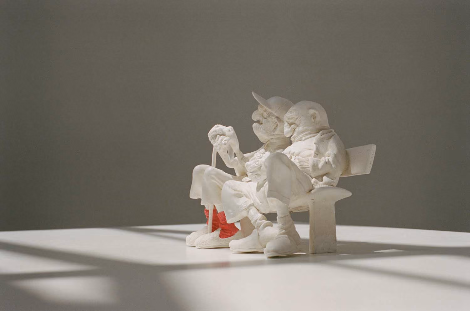 Guillermo Forchino sculpture of white figures sitting together on a bench