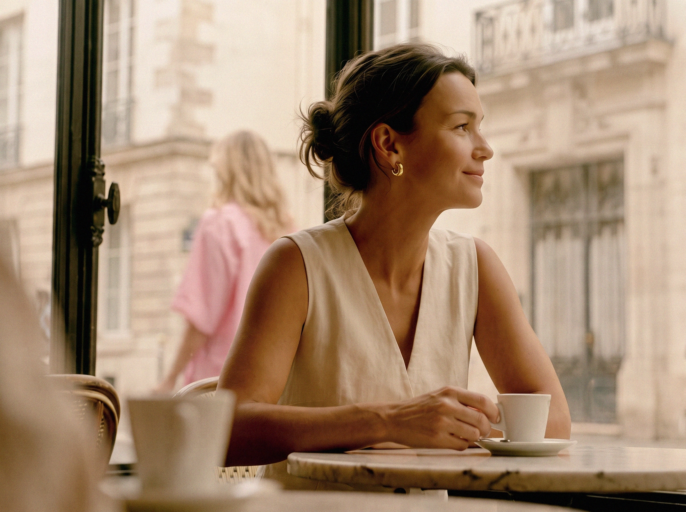 Woman with a coffee at a café table by the window