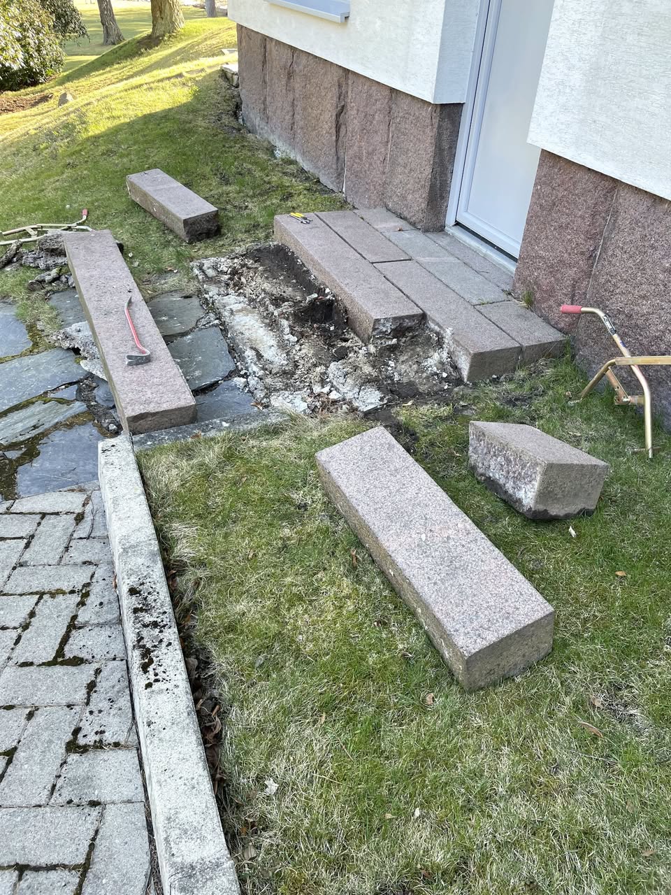 Rakennuksen sisäänkäynnin edustalla on käynnissä piharemontti, jossa graniittilohkareita on aseteltu ja maata kaivettu.