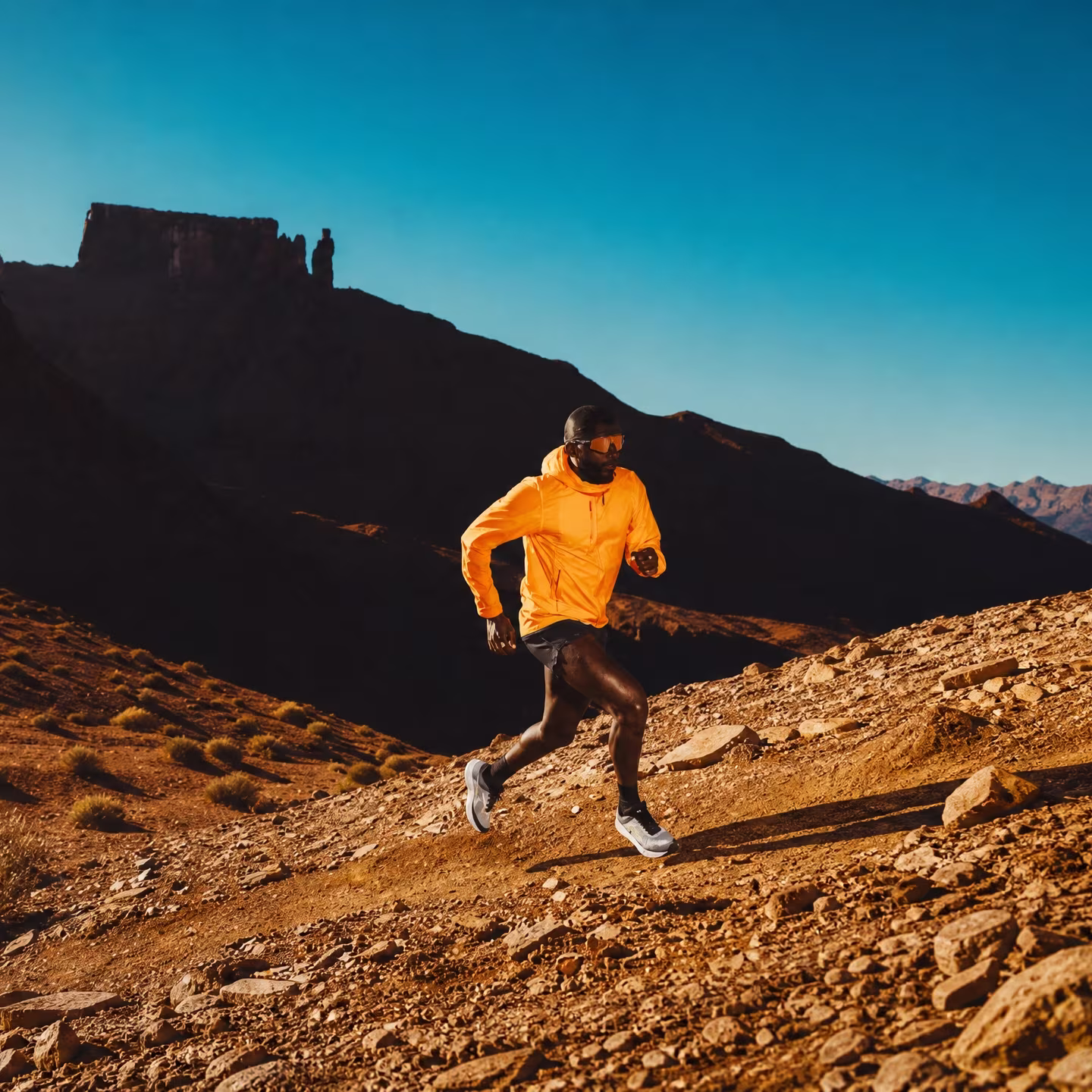 Trail runner moving through a rocky desert canyon at dusk
