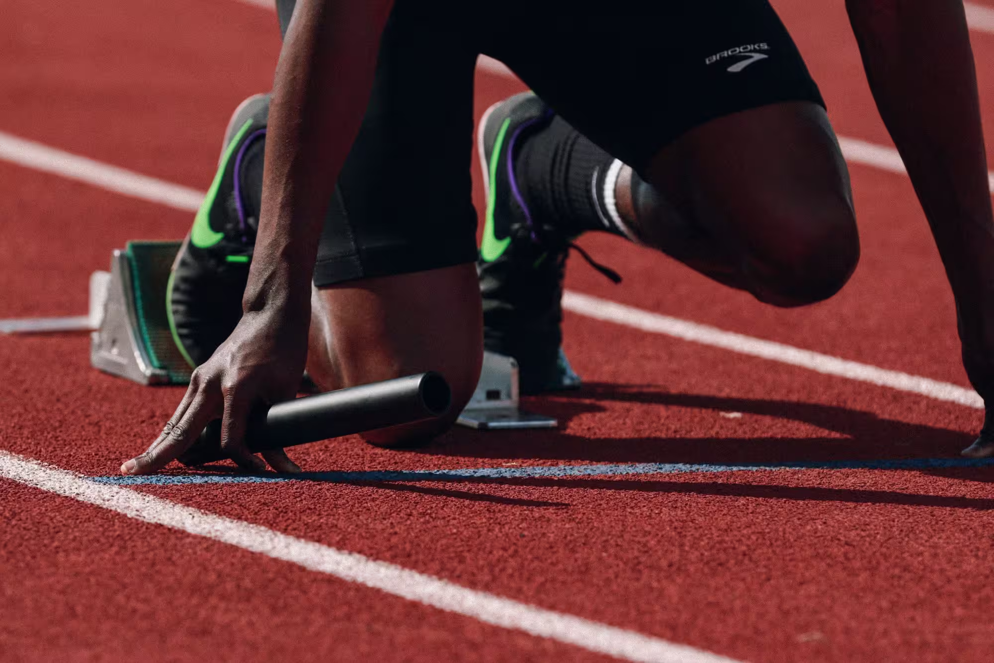 Sprinter's hand and foot in starting blocks on a track