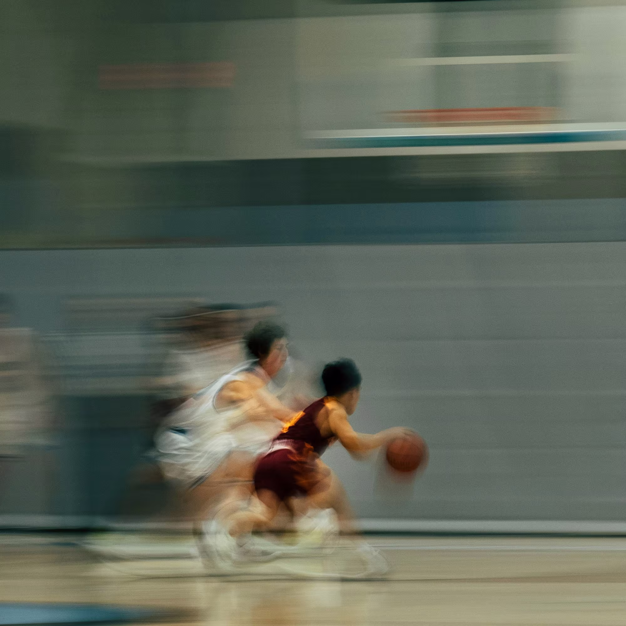 Motion-blurred basketball players driving toward the basket