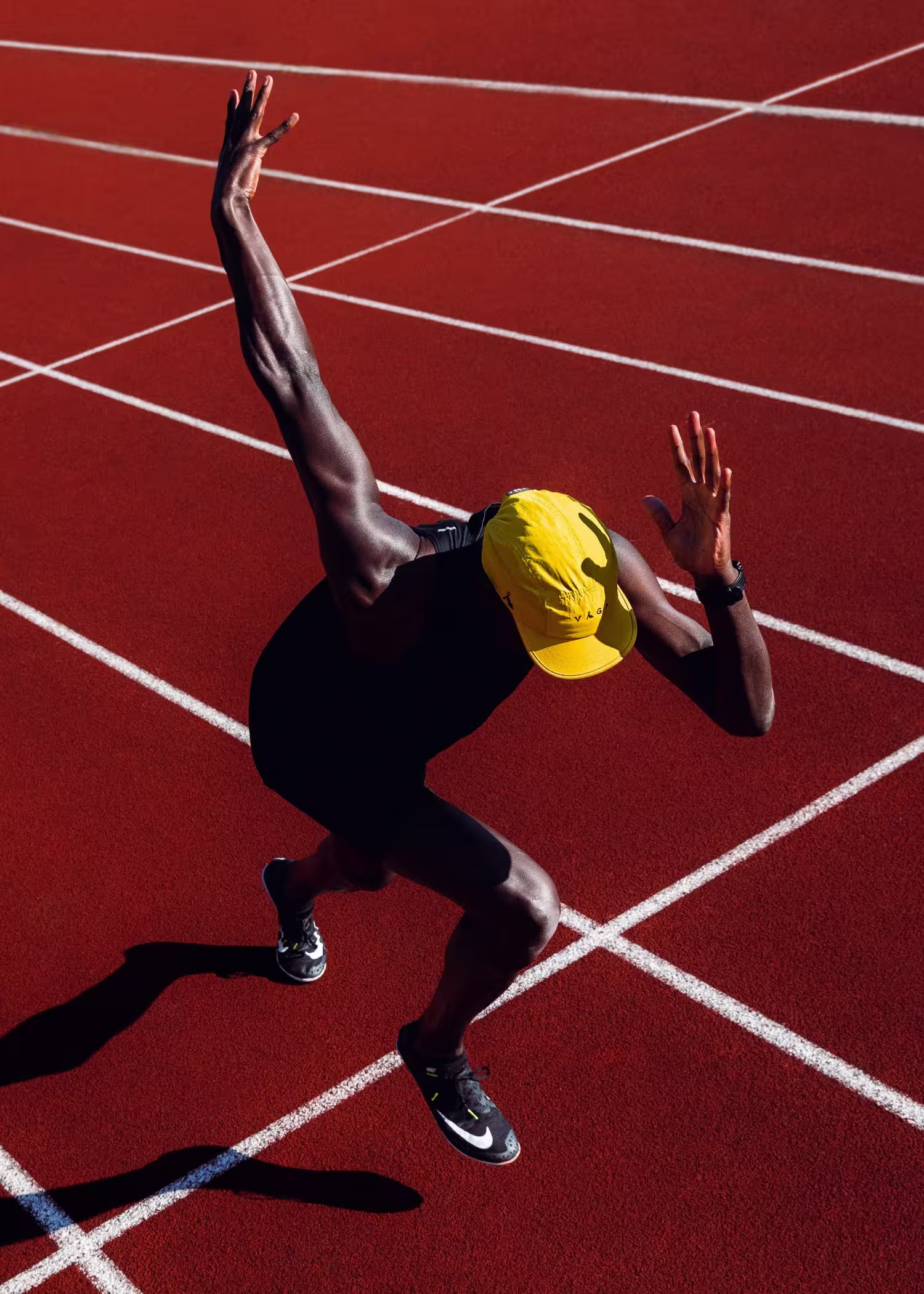 Athlete captured mid-motion in a sprint start on a red track