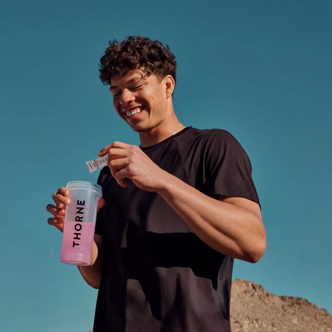 Athlete opening a nutrition supplement sachet next to a shaker bottle