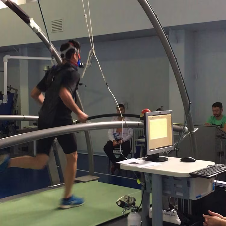 Man running on a treadmill wearing a VO2 max mask in a sports science lab