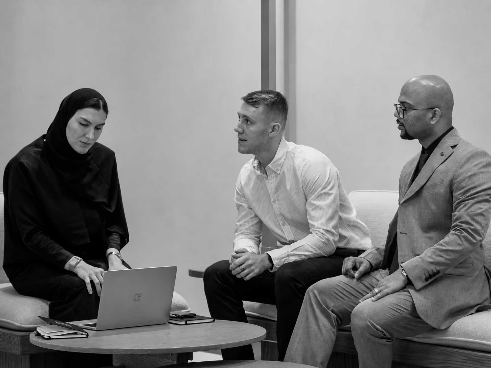 Black-and-white photo of a coaching consultation with a laptop on the table