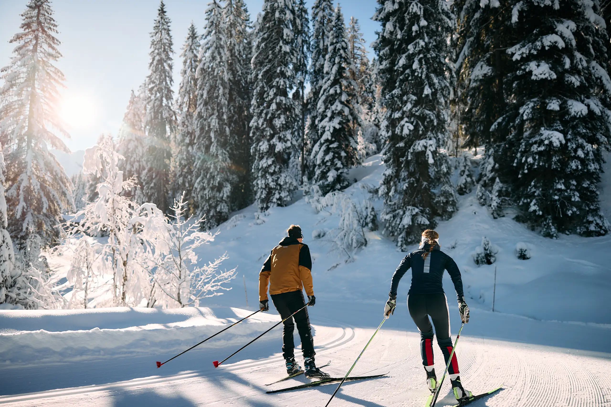 Zwei Langläufer auf der Loipe durch den verschneiten Winterwald im Kleinwalsertal