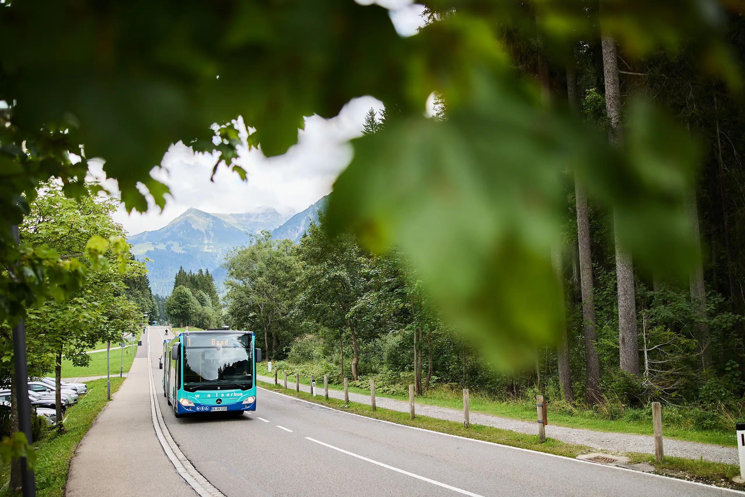 Walserbus auf der Landstraße im Kleinwalsertal mit Bergen im Hintergrund