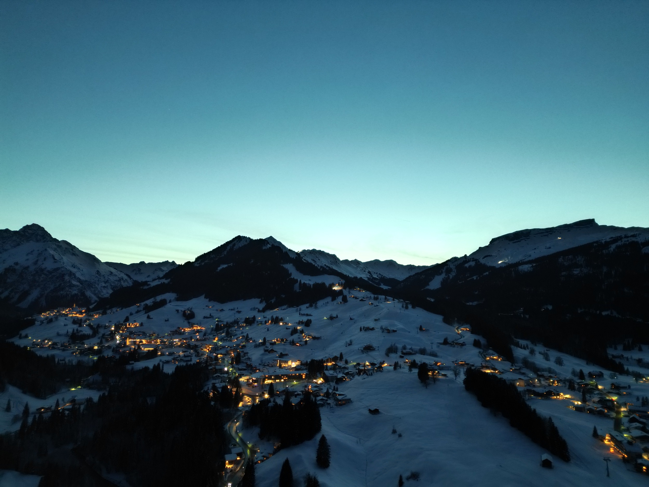 Kleinwalsertal am Abend mit verschneiten Bergen und beleuchteten Orten