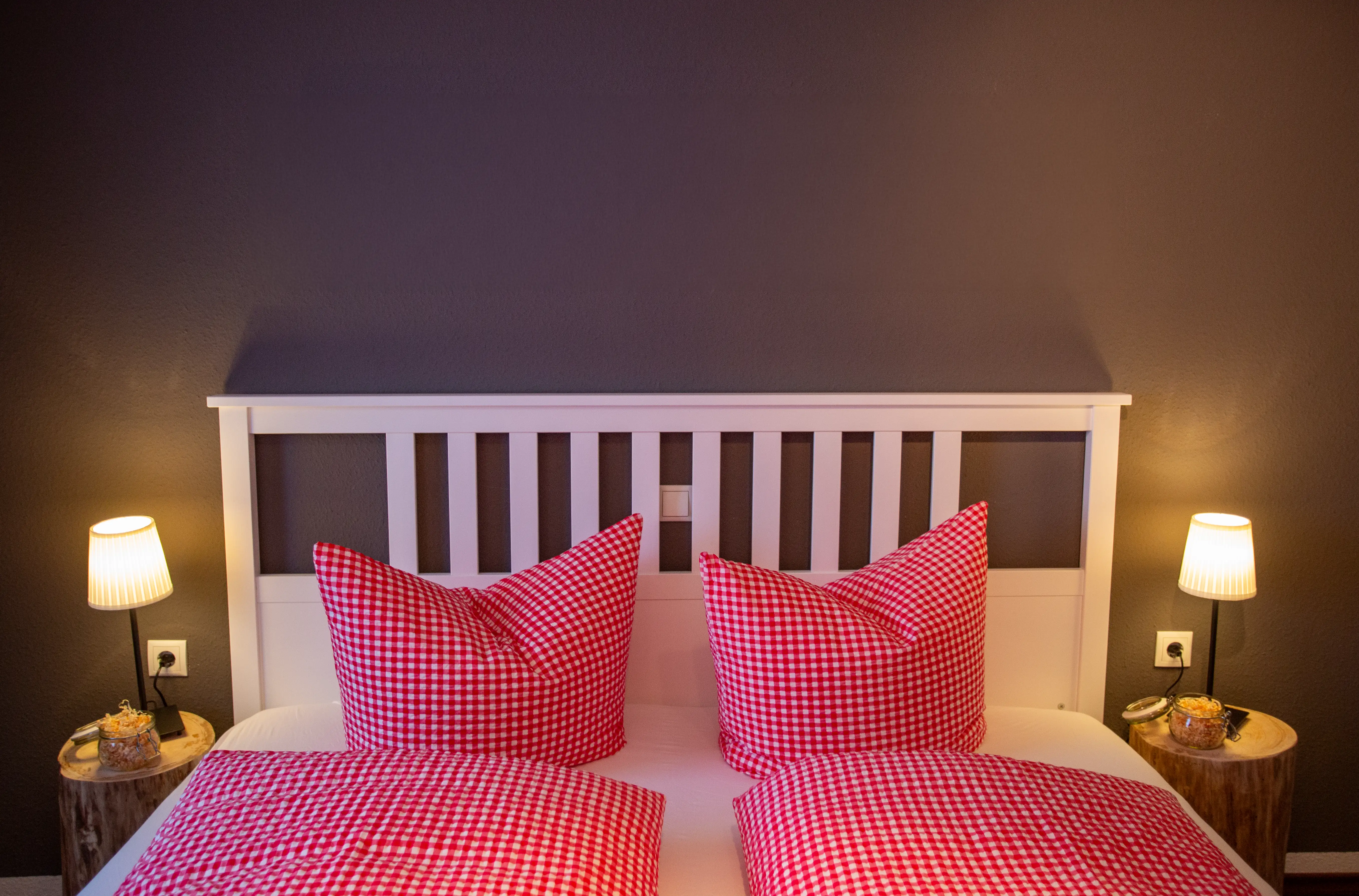 Doppelbett der Ferienwohnung Ifenblick in Hirschegg mit rot-weiß karierter Bettwäsche und Nachttischlampen