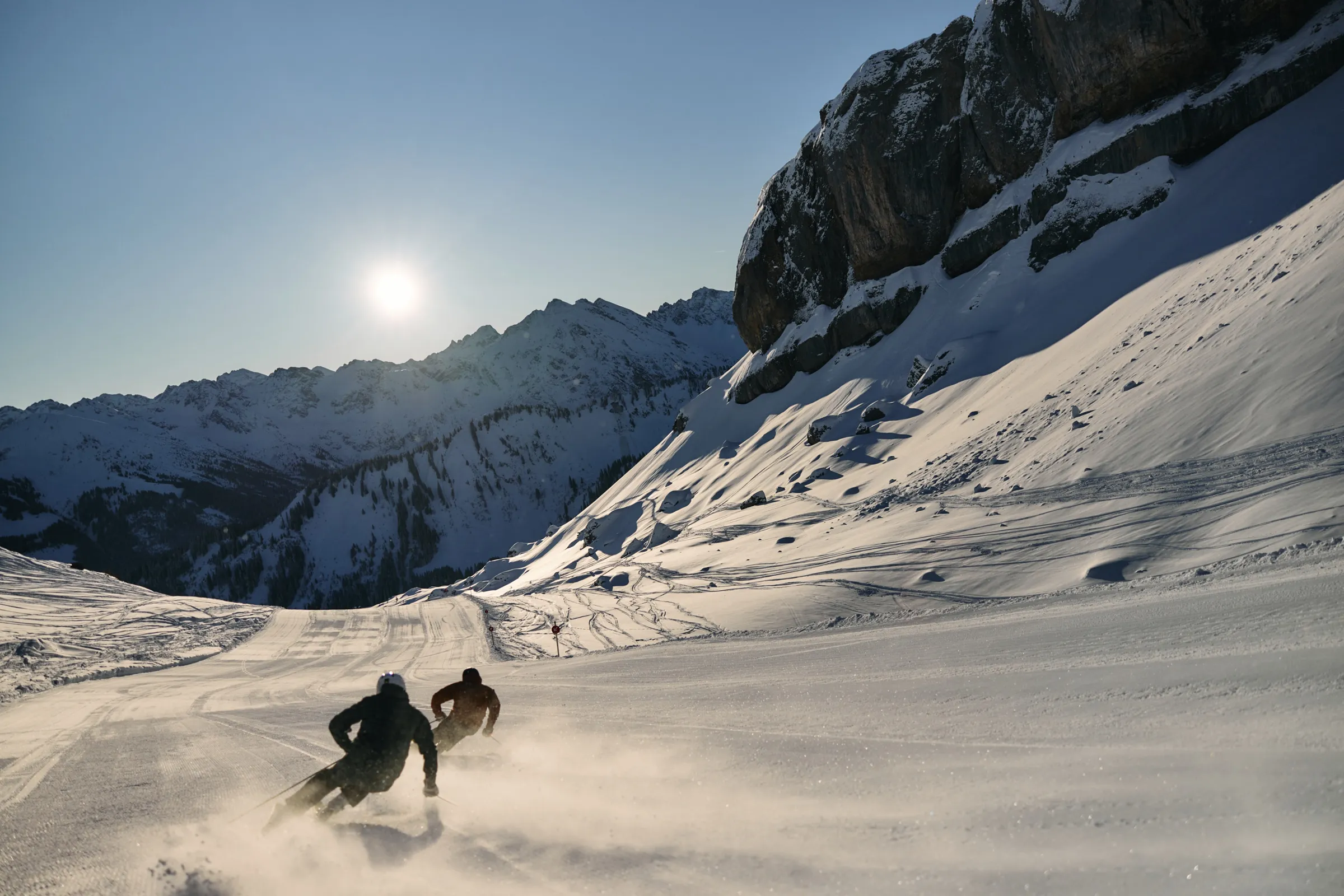 Zwei Skifahrer carven unter den Felswänden des Hohen Ifen im Kleinwalsertal