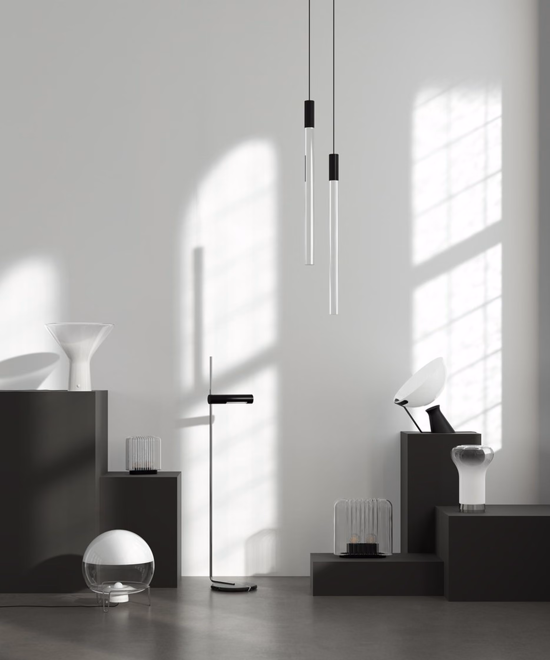 Minimalist room with a gray floor and white wall, featuring modern black pedestals displaying various contemporary lamps and lighting fixtures, including two slim hanging pendant lights, a black floor lamp, a white funnel-shaped lamp, a glass globe lamp, and other sculptural light designs, with sunlight casting window grid shadows on the wall.