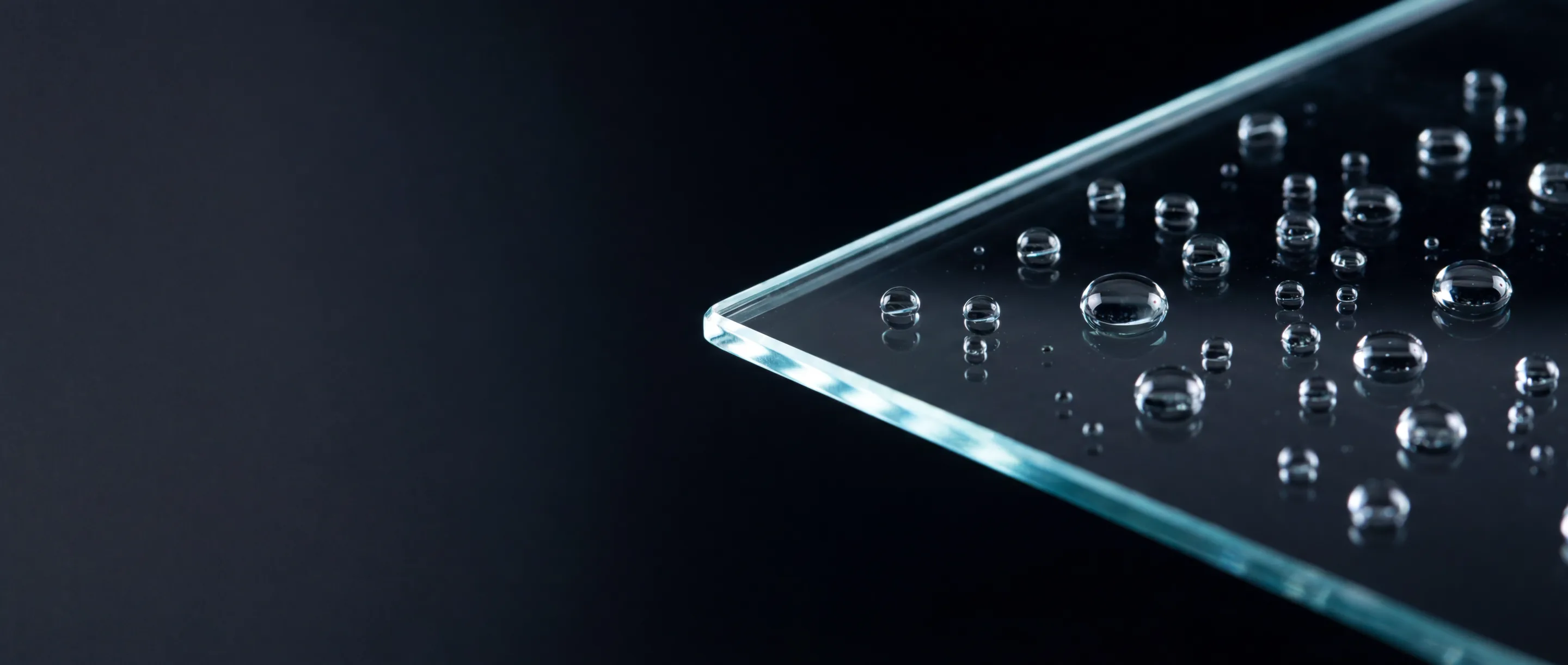 Close-up of clear water droplets on the smooth surface of a transparent glass pane.