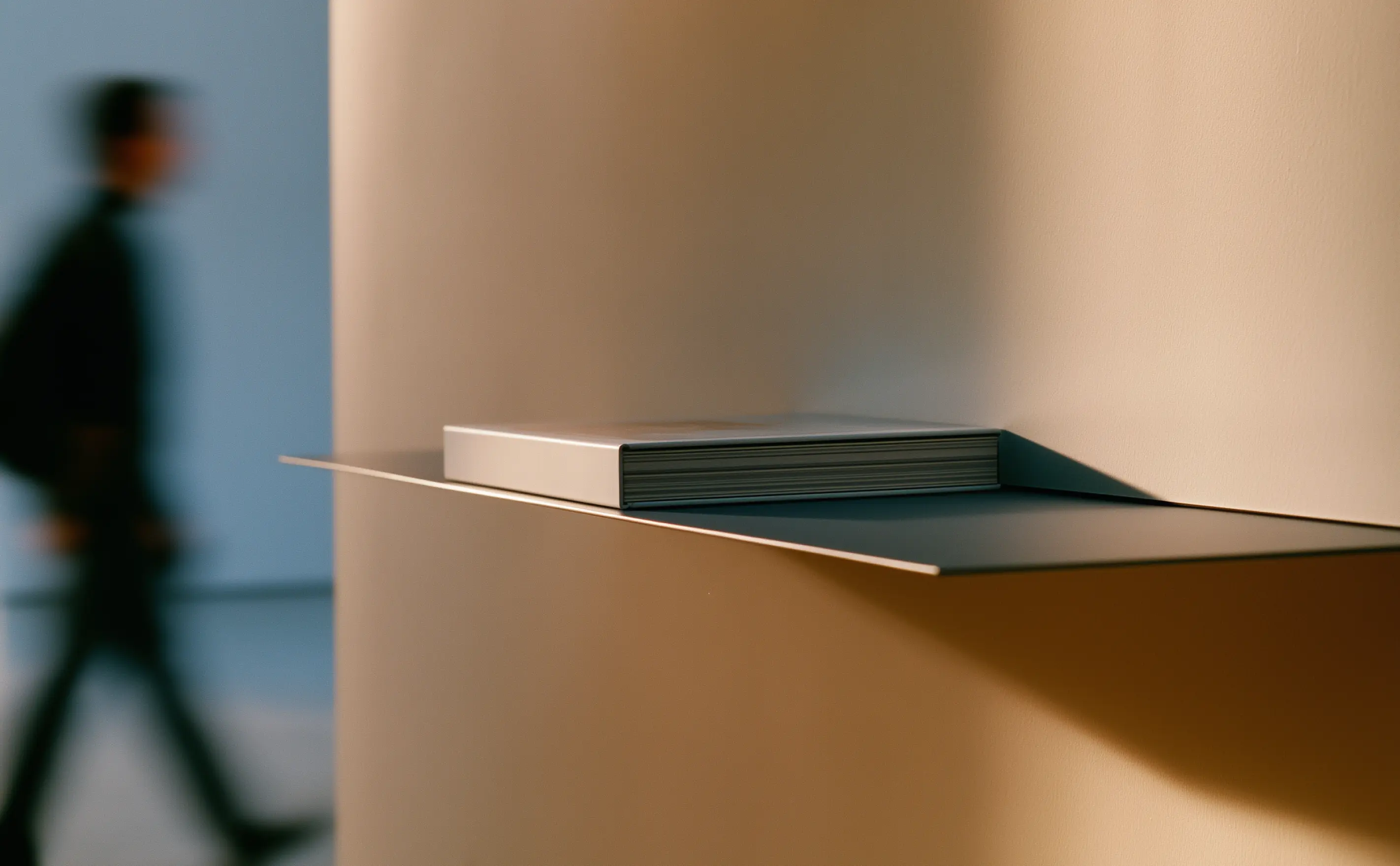 Closed brand guidelines book resting on a shelf as a blurred person walks past.