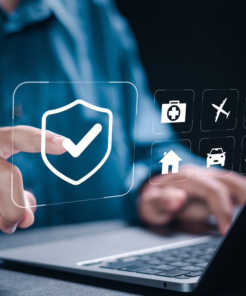 Hand at a laptop with insurance coverage icons
