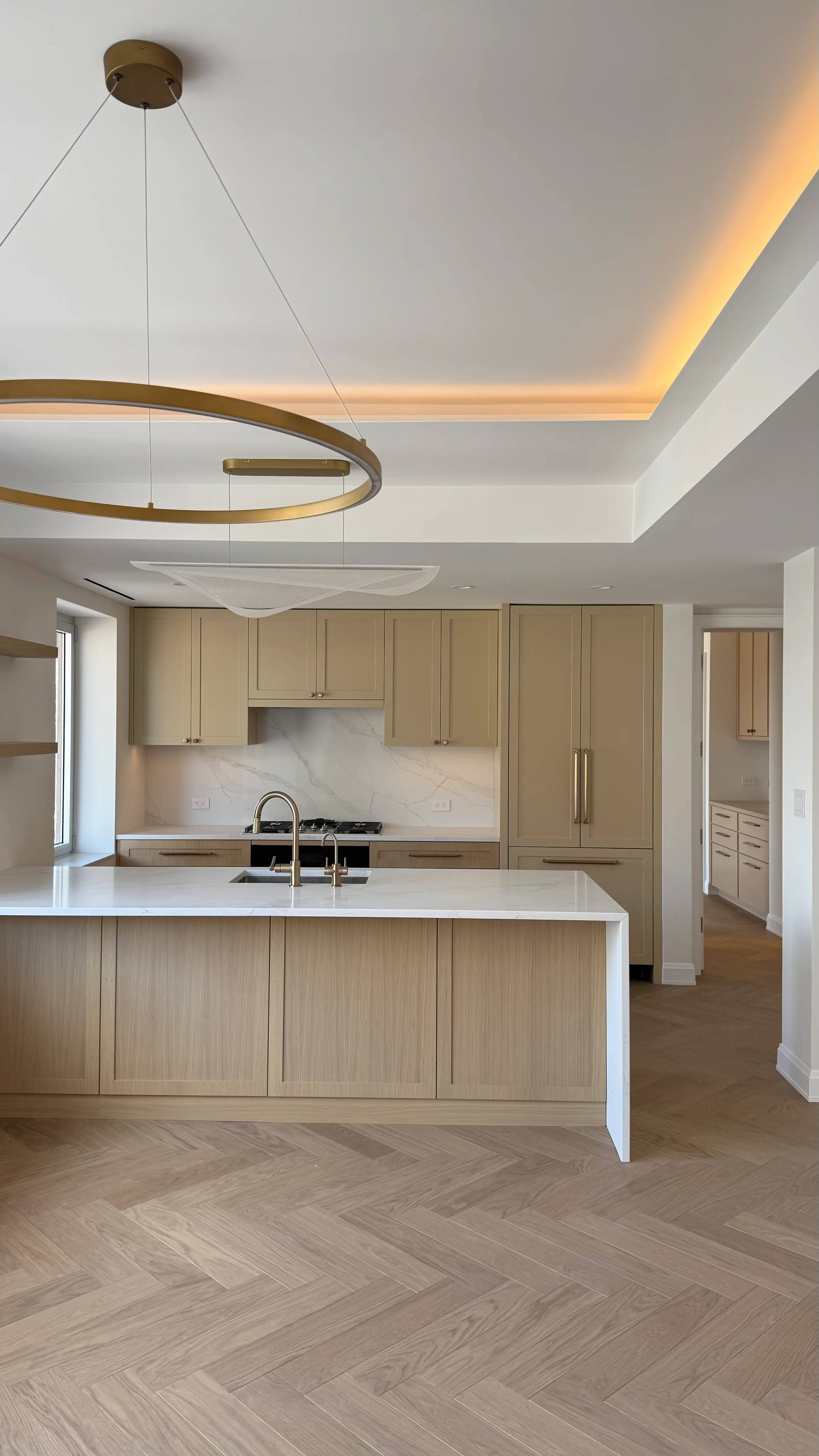 Custom kitchen cabinetry with a wood-grain island, light stone surfaces, and integrated appliances in Manhattan