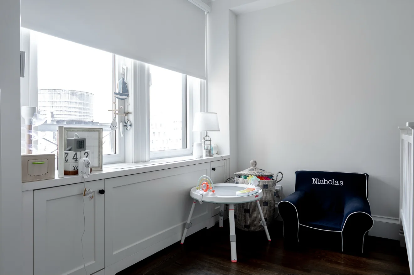 White custom built-in storage cabinetry beneath a window in a Manhattan apartment.