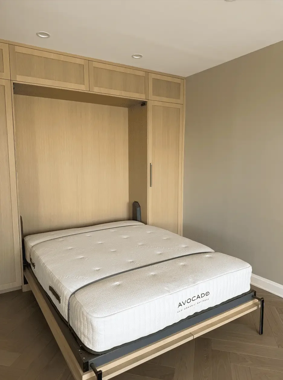 Fold-down bed integrated into light wood cabinetry with built-in storage on both sides.