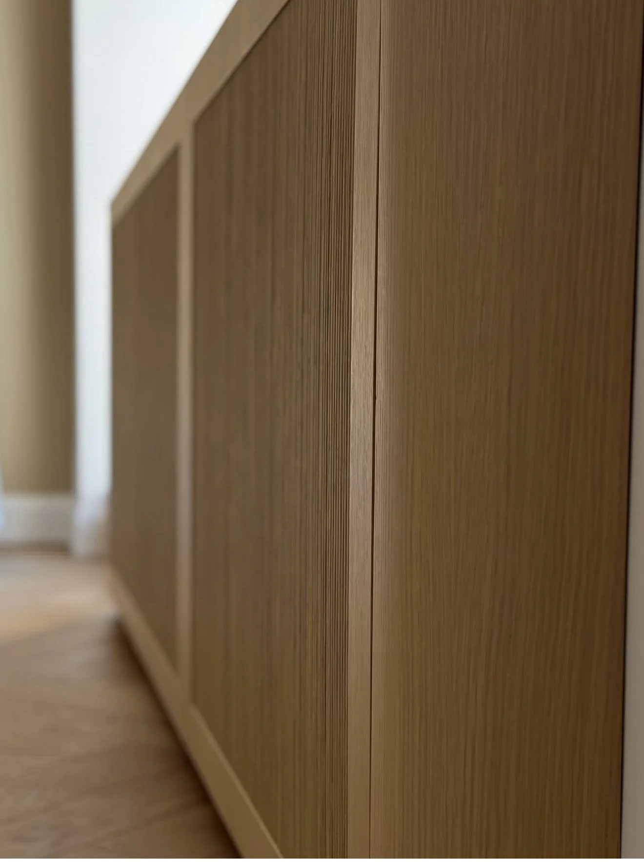 Close-up of a custom radiator cover finished in natural wood with fine vertical grain.
