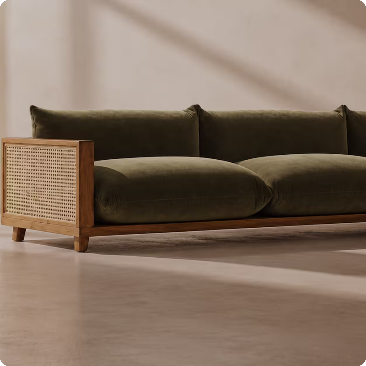 Low olive green velvet sofa with wooden frame and woven cane sides on a light floor.