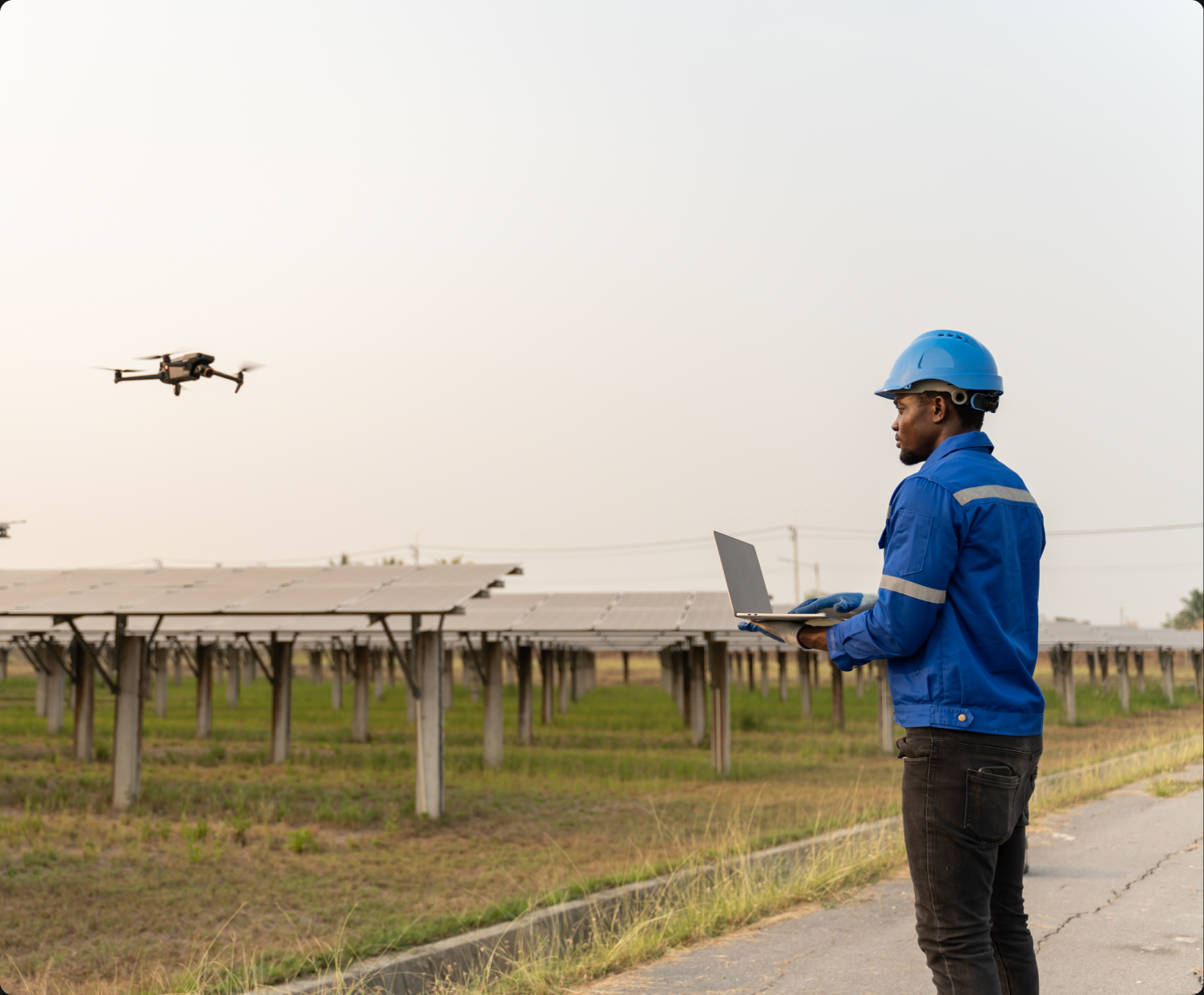 Technician flying a drone over a solar farm with a laptop