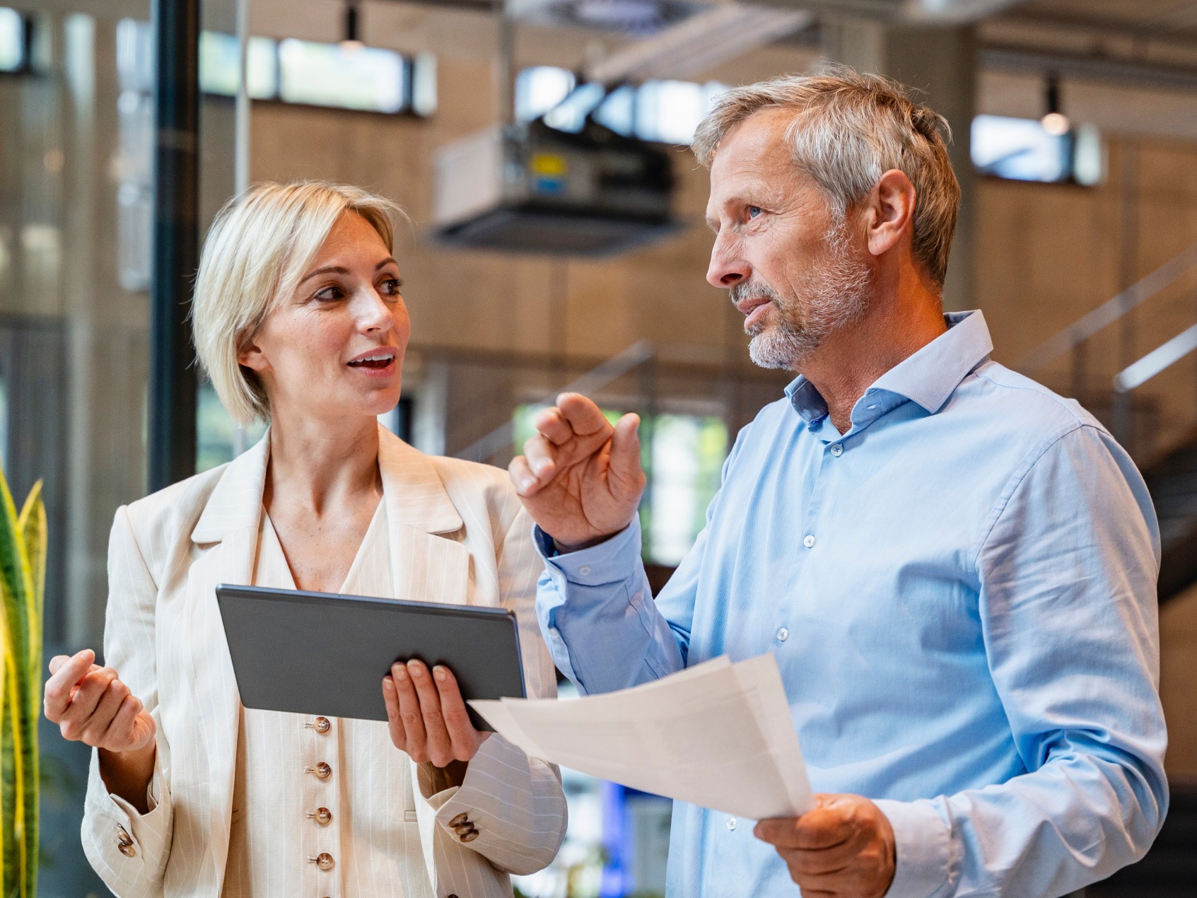 Two colleagues in conversation, one holding a tablet