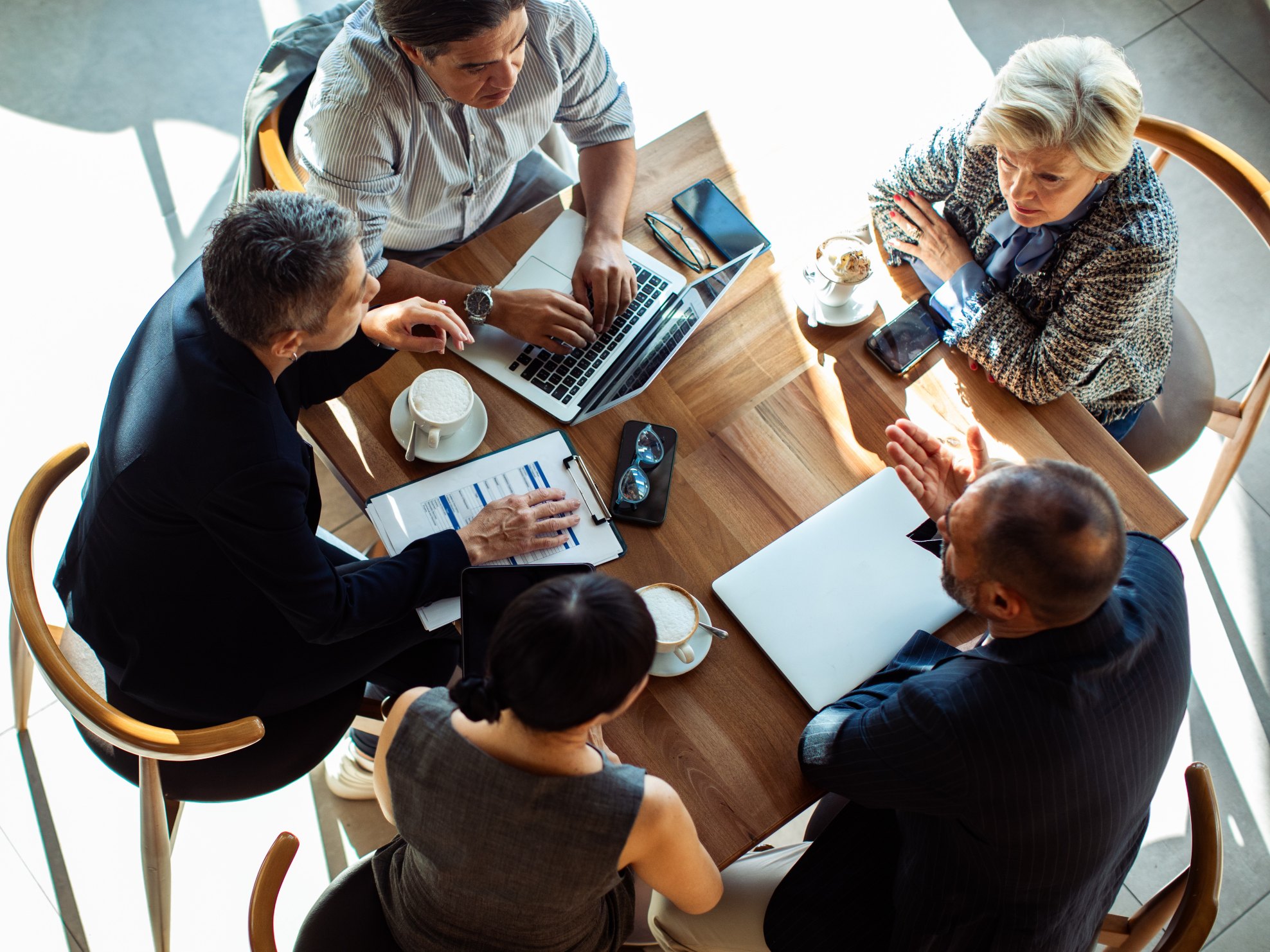 Overhead view of a team meeting around a table with laptops