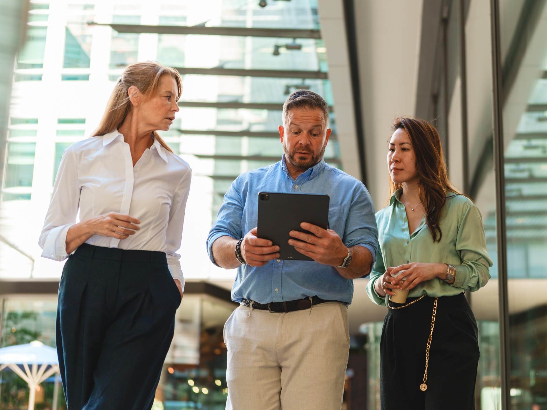 Three colleagues walking and talking, one holding a tablet