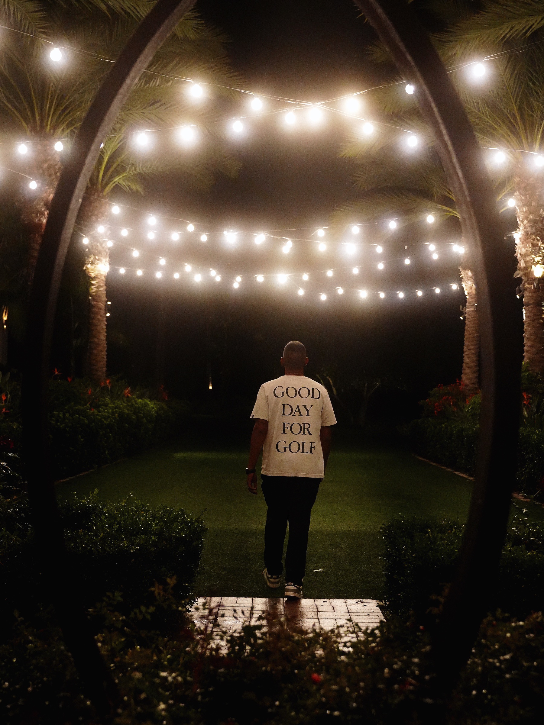 Golfer walking beneath glowing string lights at Aviara.
