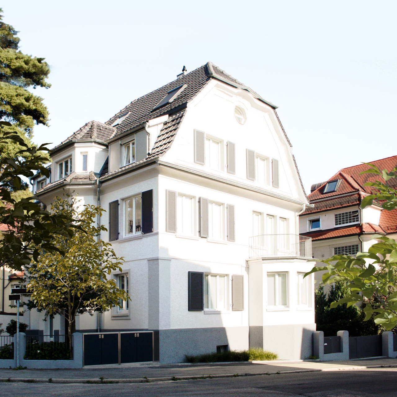 Front view of a classic beige mansion with tall windows, decorative balcony, and dormer windows on roof.