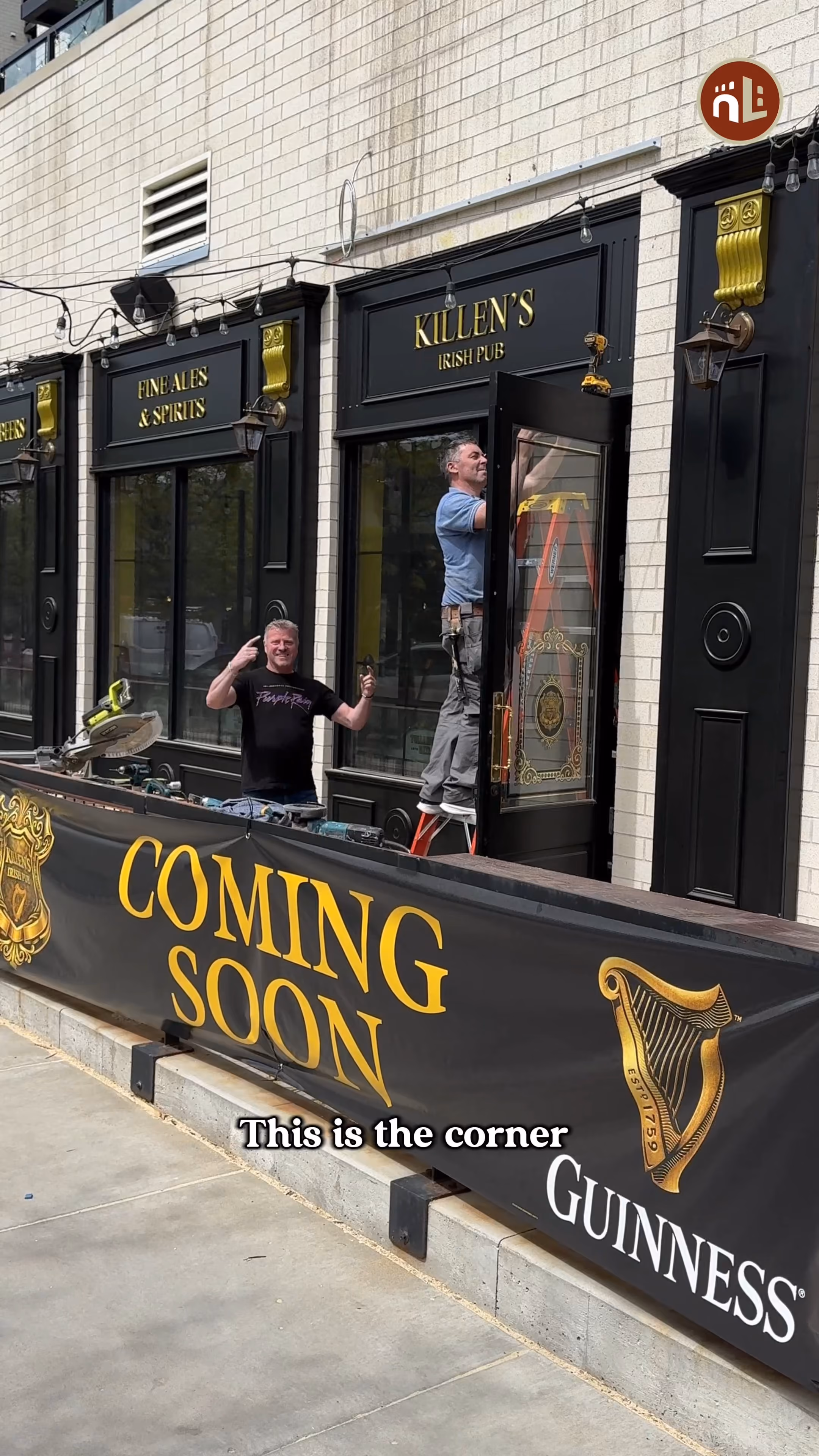 Two men working outside Killen's Irish Pub with a 'Coming Soon' Guinness banner in front.