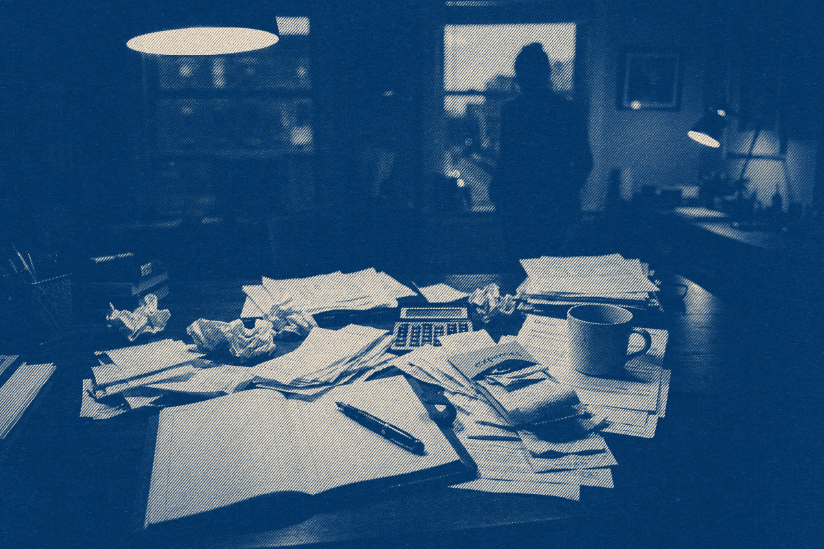 Cluttered night desk with papers and a calculator