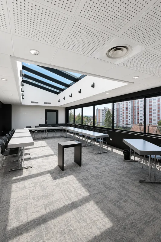 Vue d'ensemble de la salle de séminaire climatisée avec verrière, baies vitrées et moquette grise à l'Hôtel d'Alsace