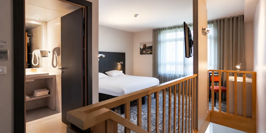 Chambre à l'étage de l'Appartement Duplex avec grand lit, rambarde en bois et salle d'eau, près de Strasbourg