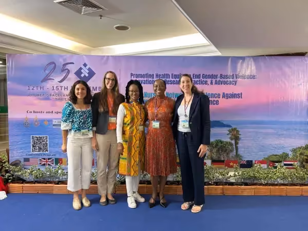 Five women pose for photo in front of backdrop at health equity and gender based violence event in Thailand